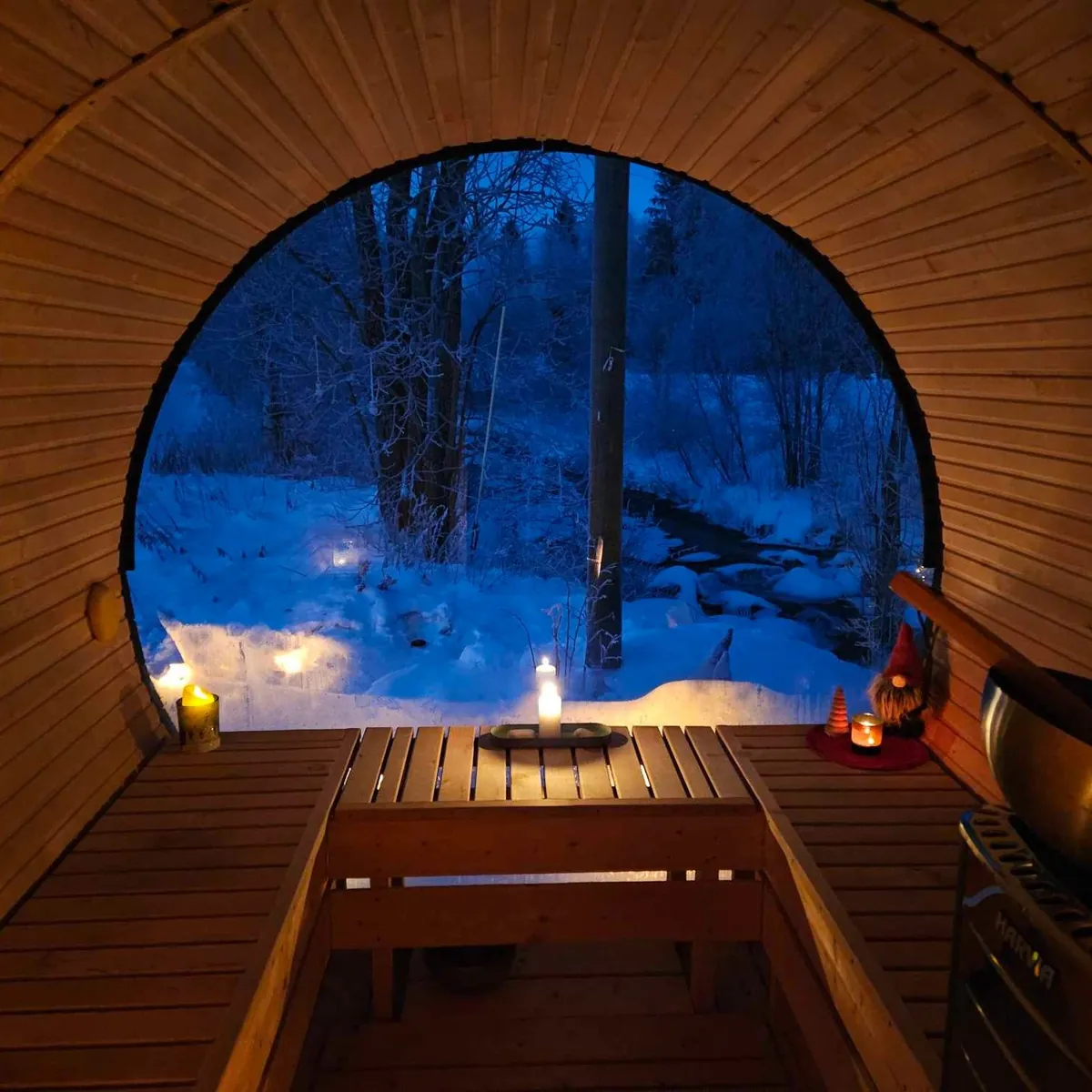 A simple community wooden sauna beside a lake in rural Norway with people relaxing outside