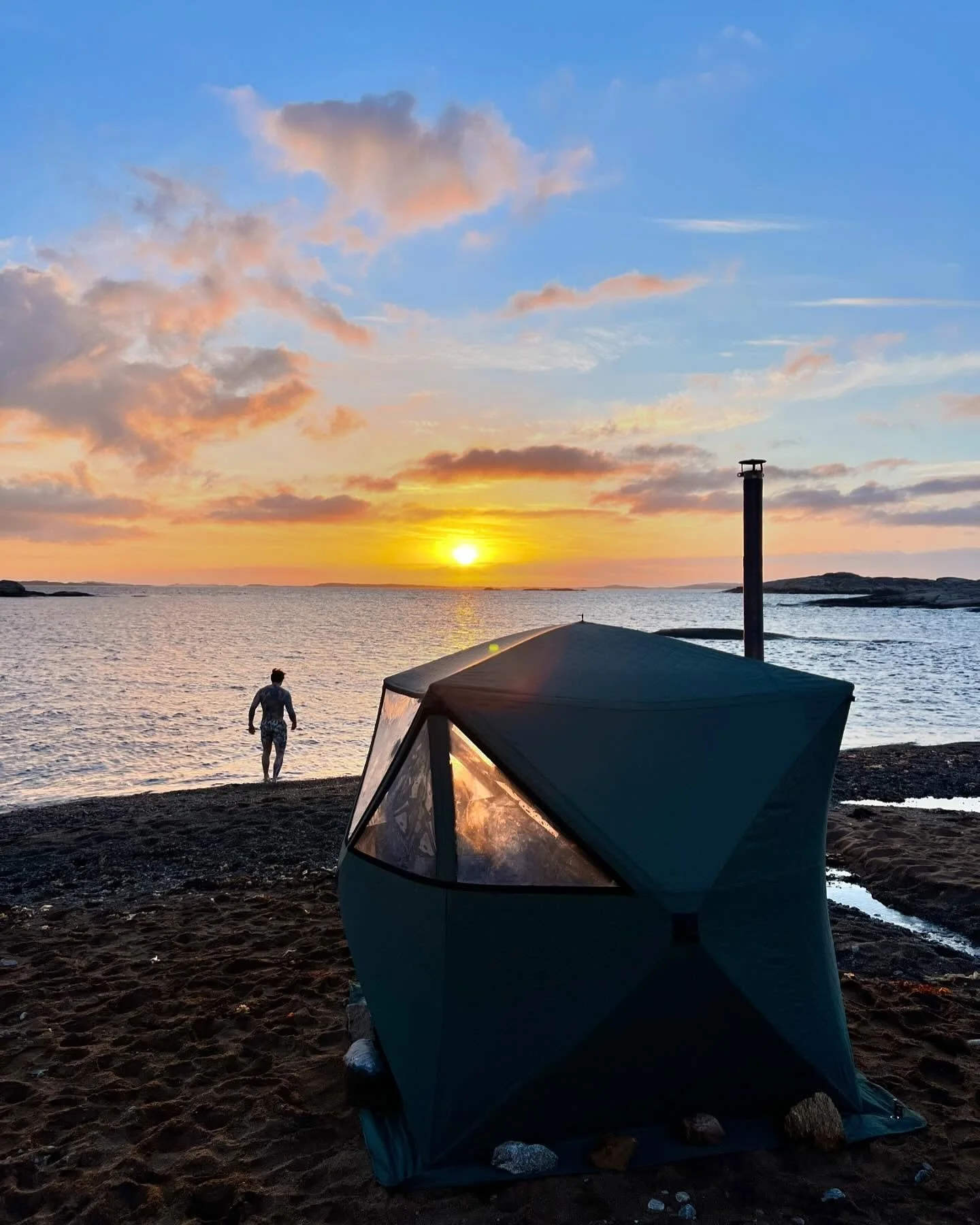 Wood-fired Norwegian sauna on a fjord shore with mountains rising behind