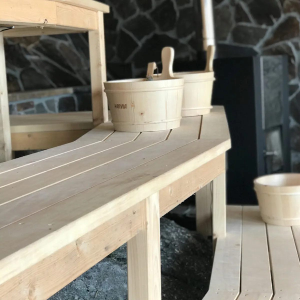 A wooden sauna cabin on an arctic fjord with the Northern Lights visible overhead
