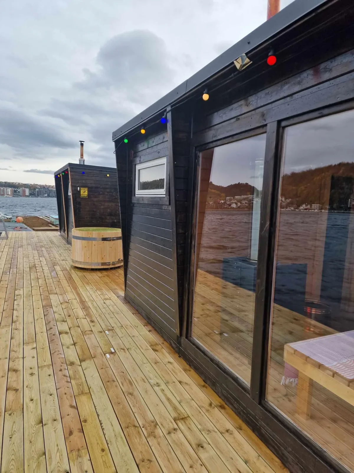 Floating sauna cabin on calm water with the flat Jæren coastline at sunset