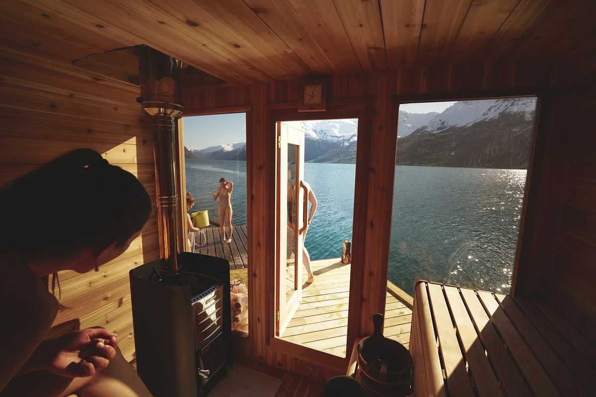 Sauna on the shore of Hardangerfjord with mountains and orchard-covered hillsides behind