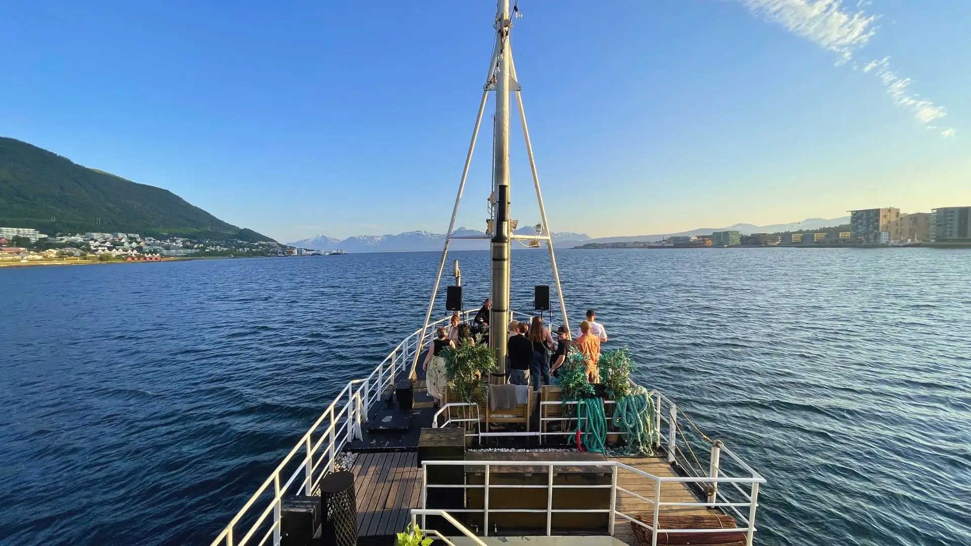 A converted Arctic fishing vessel with sauna facilities cruising through snowy fjords near Tromsø at dusk